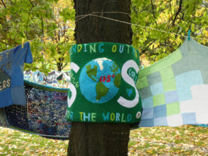 Knitted panel round a tree with words saying sending out SOS to the world